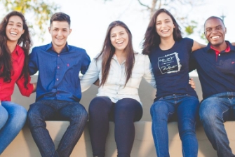 Off campus student group sits smiling outdoors